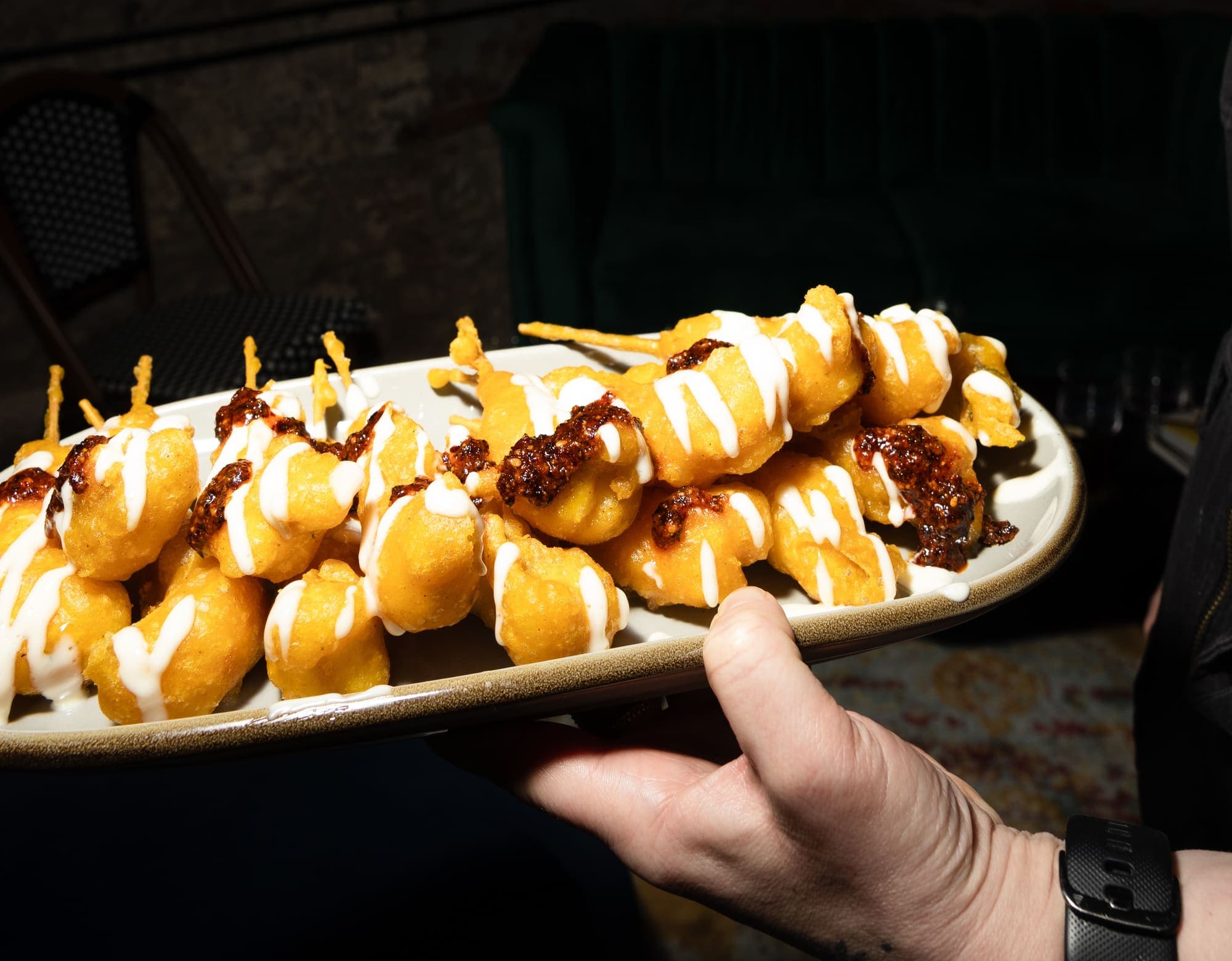 Crispy corn fritters with chili crisp and crema, passed at a private event